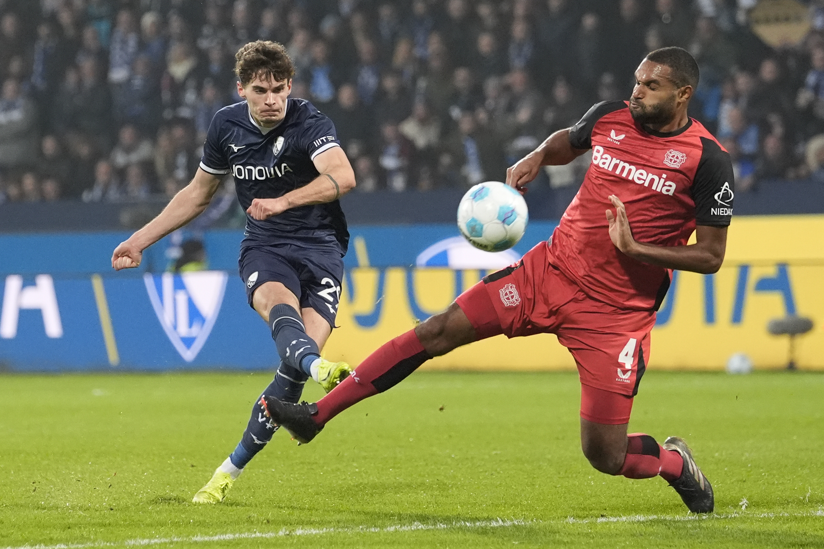 Bochum's Moritz Broschinski shooting at goal and Jonathan Tah defending against the rival opportunity.