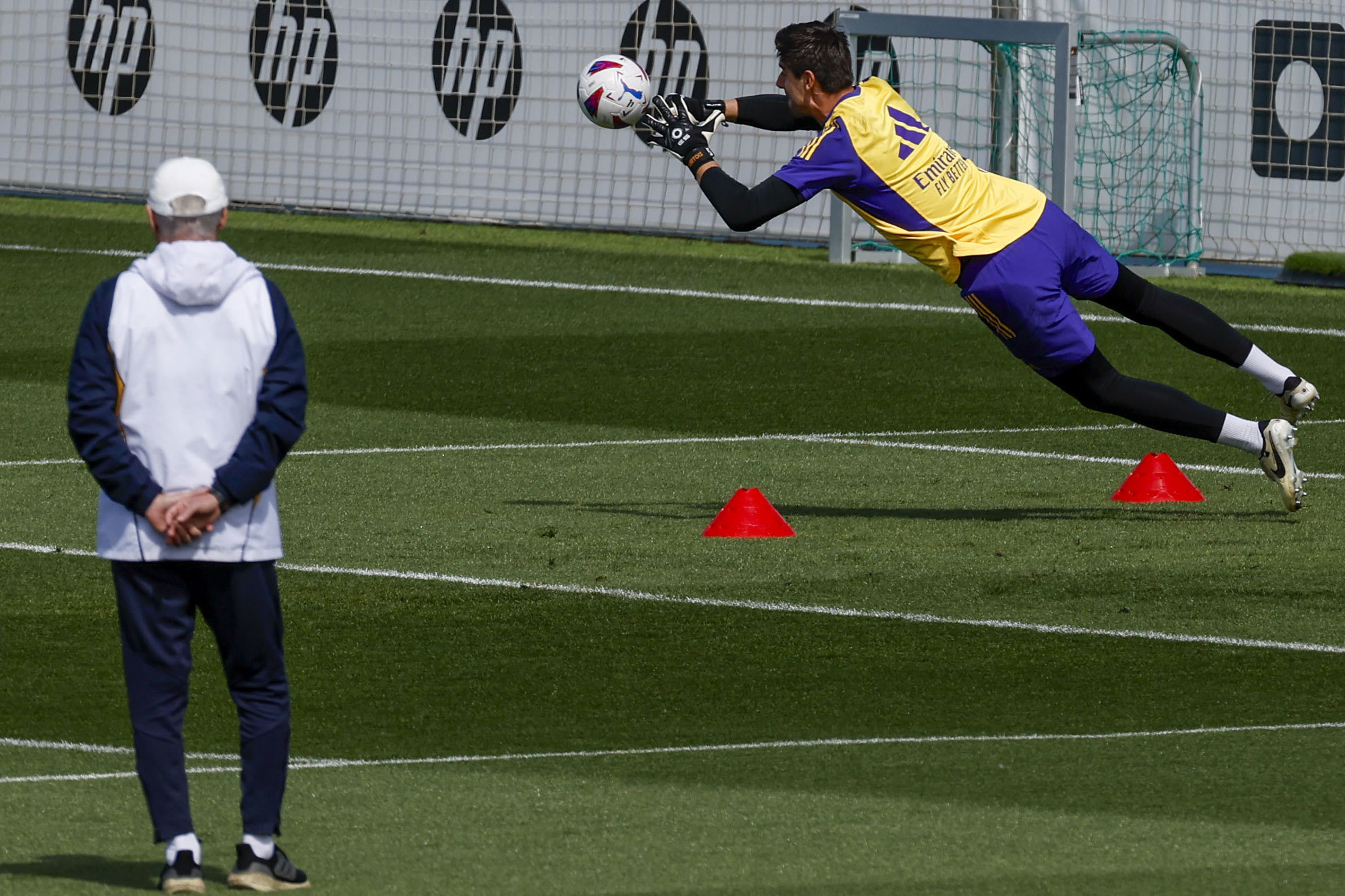 Ancelotti watches Courtois stretch in training.