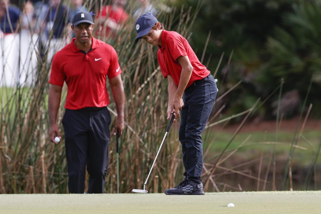 Charlie Woods makes a putt on the second green while being watched by father Tiger Woods