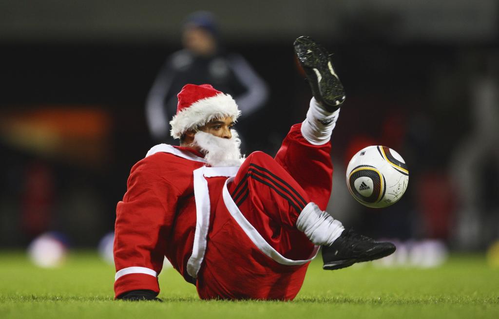 A fan dressed as Santa Claus touches a ball.