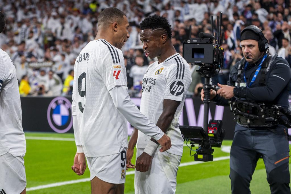 Mbappé y Vinicius celebran un gol en Liga mientras un cámara de tv les graba.